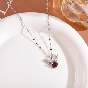 Detail of deer antler pendant with a red stone and crystal accents on a silver chain