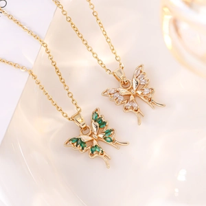 Close-up of gold butterfly necklaces with green and white cubic zirconia gemstones