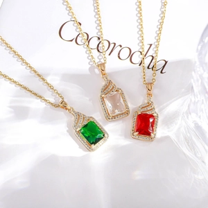 Detailed shot of emerald, ruby, and crystal square pendants with pavé diamonds on gold chains