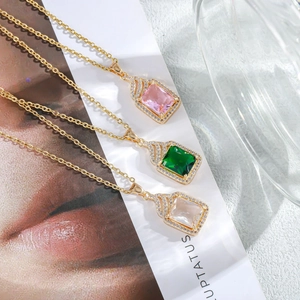 Macro detail of three colorful square zircon pendants with gold chains and crystal halos