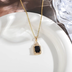 Macro view of gold chain with rectangular black gemstone pendant and tiny white diamonds