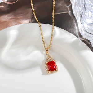 Macro shot of gold necklace featuring a rectangular red gemstone pendant with diamond halo