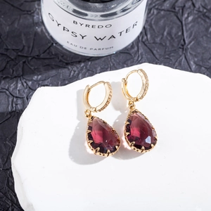 Macro shot of gold teardrop earrings with crimson gemstone and micro-pave crystals