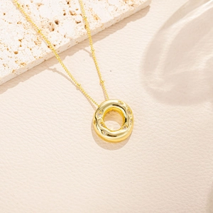 Dettaglio di una collana con ciondolo circolare dorato e zirconi scintillanti su catena sottile