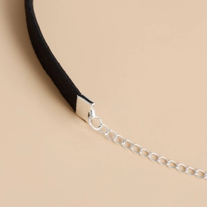 Primer plano detallado de un choker de terciopelo negro con cadena ajustable de metal plateado