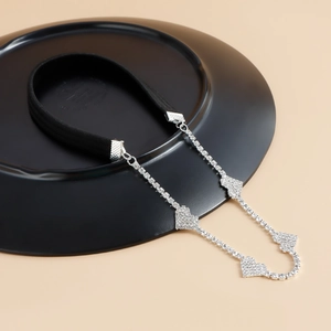 Elastische zwarte beenketting met zilveren hart-steentjes op een zwarte display