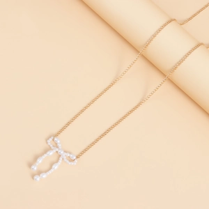 Détail de chaîne de taille dorée avec nœud en perles élégantes sur un support minimaliste
