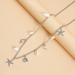 Detailed shot of silver beach body chain featuring seashells, starfish and dolphin charms