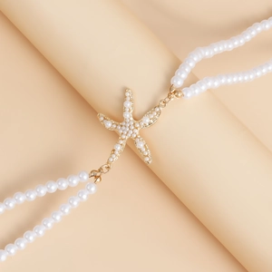 Detailopname van de dubbele parelketting met een gouden zeester hanger voor strandkleding