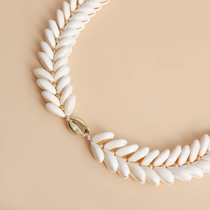 Detailed macro view of woven natural cowrie shells with gold beads on beach waist chain