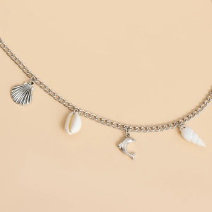 Detail of silver chain body jewelry featuring seashell starfish and dolphin pendants