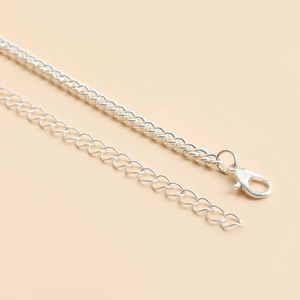 Detailed close-up of the silver lobster clasp and extension chain on the body jewelry