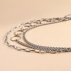 Macro detail of layered silver body chain featuring engraved rings and metallic textures