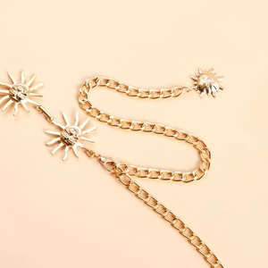 Detailed view of a gold-tone metal sun charm belt with adjustable lobster clasp links
