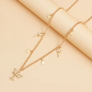 Close-up of golden body chain featuring star charms and winged angel pendant on a prop