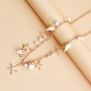 Détail d'une chaîne de taille dorée avec coquillages, étoiles de mer et perles