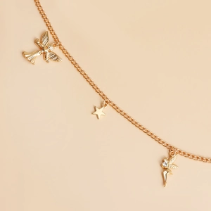 Detailed close-up of golden belt chain featuring angel star and fairy charms with rhinestones
