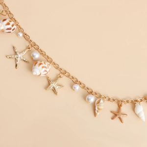 Détail de chaîne de corps dorée avec coquillages naturels, perles et breloques étoile