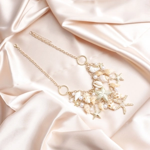 Détail de la chaîne de taille bohème dorée avec pendentifs coquillages et étoiles de mer