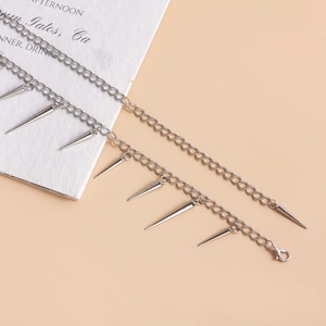 Close-up of silver punk body chain featuring seven sharp conical spikes and lobster clasp