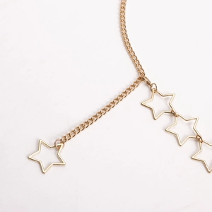 Macro shot of gold-tone waist chain featuring hollow star charms with metallic luster