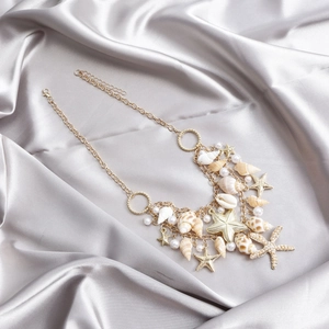 Détail de la chaîne de taille bohème dorée avec coquillages, étoiles de mer et perles