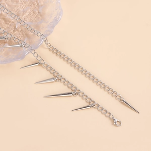 Close-up of silver punk body chain featuring sleek cone spike charms and a lobster clasp