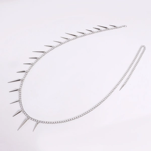 Macro shot of silver punk body chain featuring sharp metallic cone spikes and polished links