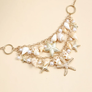 Détail macro d'une chaîne de corps bohème dorée avec étoiles de mer et perles