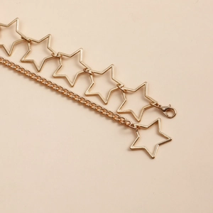 Detail of gold hollow star chain with layered curb links and lobster clasp closure