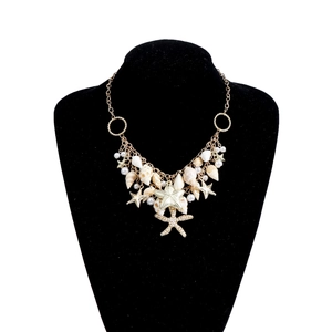 Détail de chaîne de corps avec coquillages naturels, étoiles de mer dorées et perles