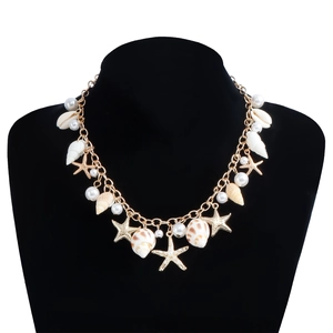 Détail d'une chaîne de corps dorée avec pendentifs coquillages, étoiles de mer et perles