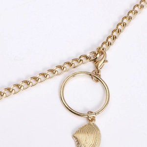 Détail du pendentif coquillage doré et du fermoir mousqueton sur chaîne de corps
