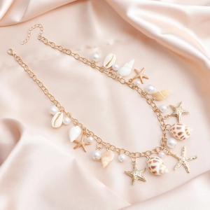 Détail de la chaîne de taille bohème dorée avec coquillages, étoiles de mer et perles