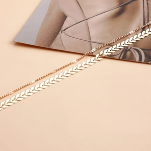 Detail of layered gold waist chain featuring a sleek thin link and V-shaped geometric pattern