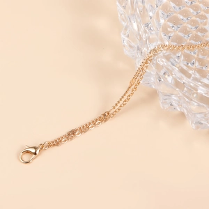 Detail of a multi-layer gold waist chain with lobster clasp on a beige background