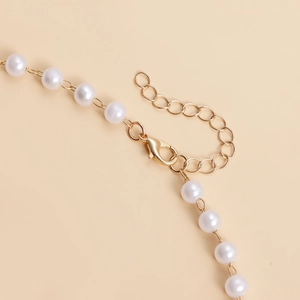 Détail d'une chaîne de corps bohème avec fermoir mousqueton doré et perles blanches