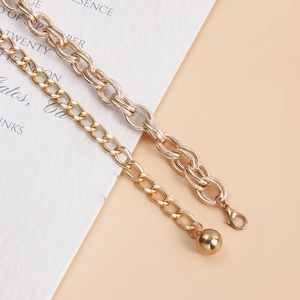 Detailed close-up of golden chunky chain body jewelry with textured links and orb pendant