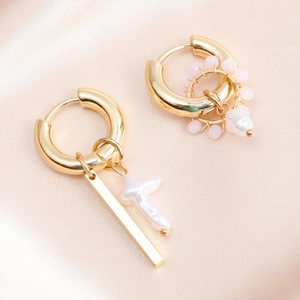 Detail of asymmetric gold hoop earrings with baroque pearl and pink bead charms