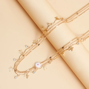 Detail of multi-layer gold body chain with metal butterflies, daisies and rhinestones