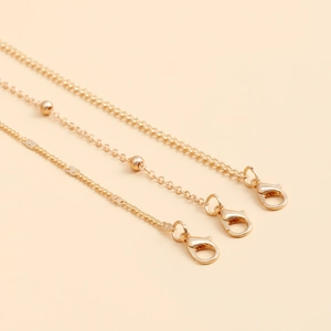 Detail view of layered gold-tone body chains with lobster clasps and bead elements