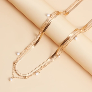 Detail of layered gold snake chain with white teardrop pearls and round metallic beads