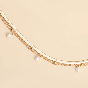 Close-up of golden multi-layered waist chain with faux pearls and elegant snake chain