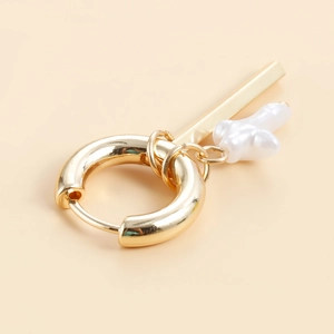Detail of gold chunky hoop earrings with baroque pearl charms on a beige background