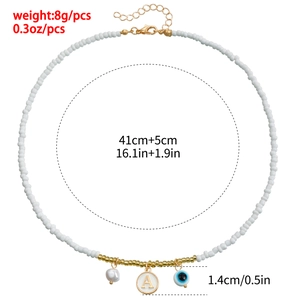 Bohemian white beaded necklace with gold charms, pearl and evil eye pendant detail