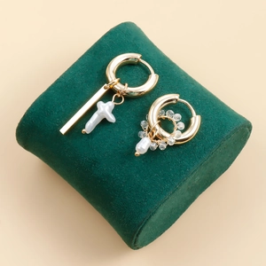 Detailed view of asymmetric gold-plated earrings with baroque pearls and cross charms
