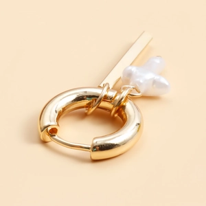 Detail view of gold hoop earring with sleek metal bar and white baroque pearl pendant