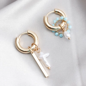 Detail view of gold hoop earrings with white pearls and light blue beads on silk