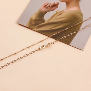 Détail de la double chaîne en or rose avec un pendentif infini serti de cristaux