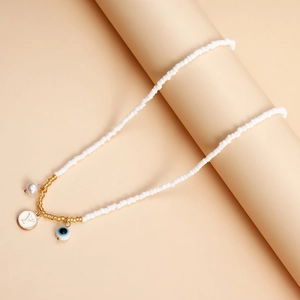 Detail of bohemian necklace with white beads, gold accents, Y letter and evil eye charms